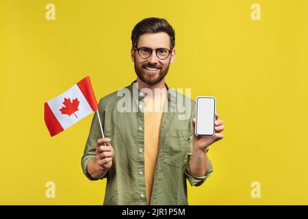 Online learning concept. Happy man holding smartphone and Canada flag, recommending mobile app, mockup Stock Photo