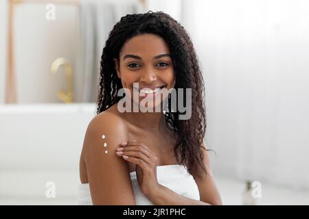 Beautiful Young Black Female Applying Moisturising Cream On Body After Bath Stock Photo