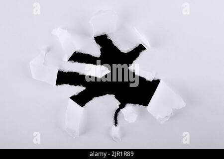 Torn paper inside a black hole in a hole. Banner. Dark torn hole in white paper. Hole paper isolated on white background with space for text. Stock Photo