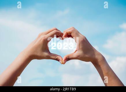Heart shape hand on blue sky and fluffy cloud background, concept of love, relationship and romantic. Female hand making finger love sign with copy sp Stock Photo