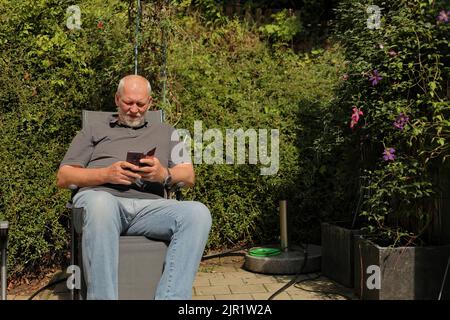 Man on the terrace reads e-mails on a smartphone Stock Photo