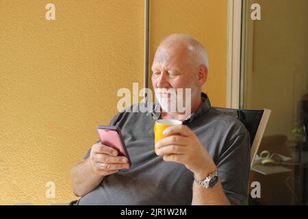 man drinks coffee on the balcony while reading email Stock Photo