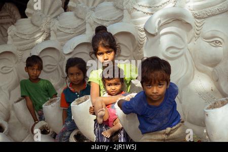 Pileru, India - July 28,2022:Bunch of Indian street kids sitting on ganesha idols.girl holding baby in the hands. Stock Photo