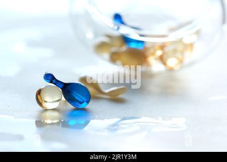 Various serum capsules for healthy skin routine. Blurred background, glass jar with the capsules on wet table. Stock Photo