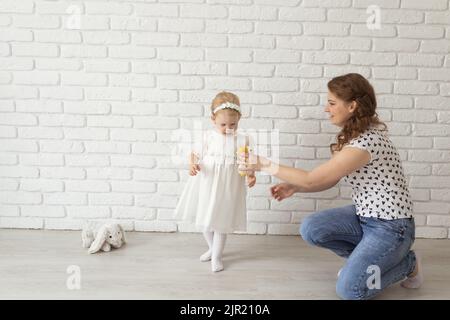 Banner baby child with hearing aids and cochlear implants plays with parents on floor, copy pace and place for advertising. Deaf and rehabilitation Stock Photo