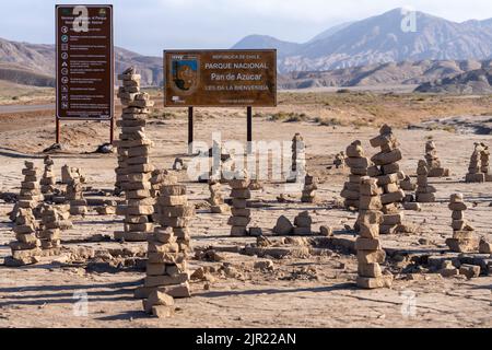 Rock cairns and a sign at the entrance to Pan de Azucar National Park in the Atacama Desert of northern Chile. Stock Photo