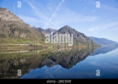 Reflection of the surrounding mountain ranges in the dark water of Lake Idro, landscape photography, Northern Italy Stock Photo