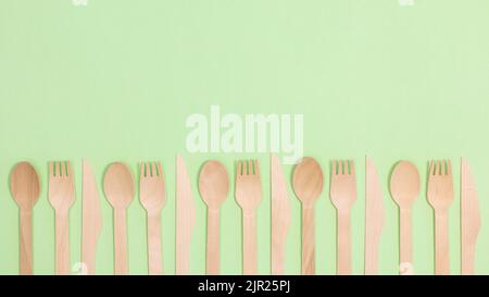 Wooden eco friendly spoons and forks on pastel green background. Flat lay Stock Photo