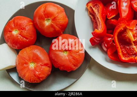 Boiled tomatoes on a plate with sliced red pepper, top view Stock Photo