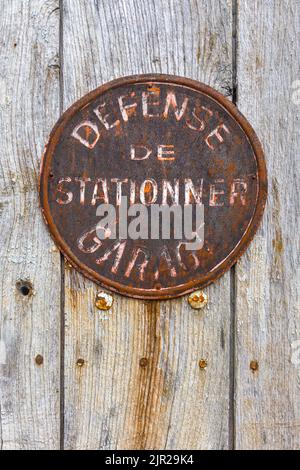 Old rusty French no parking sign on garage door - Compreignac, Haute-Vienne (87), France. Stock Photo