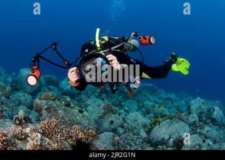A diver (MR) lines up over a reef with his digital SLR camera in an underwater housing with twin strobes. Kona Coast, Hawaii. Stock Photo