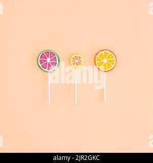 Three fruity lollipops on beige background. Flat lay Stock Photo