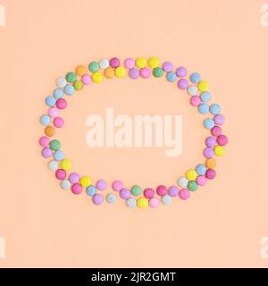 Colorful candies make frame on beige background. Flat lay Stock Photo