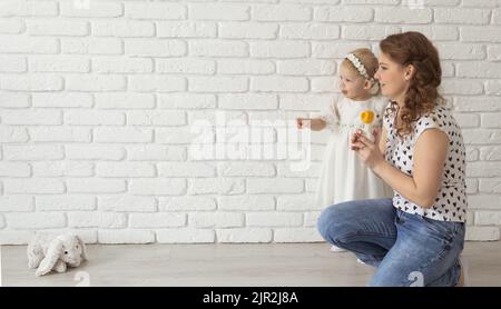 Banner baby child with hearing aids and cochlear implants plays with parents on floor, copy pace and place for advertising. Rehabilitation and Stock Photo