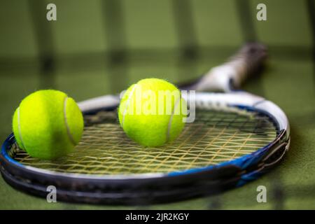 Symbol image Tennis: Close-up of a tennis racket and two tennis balls in an indoor tennis court Stock Photo