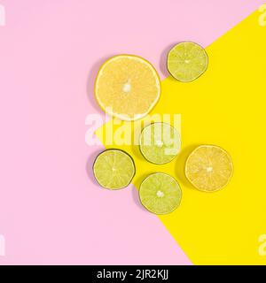 Sliced limes and lemons arrangement on pastel pink and yellow background. Flat lay Stock Photo