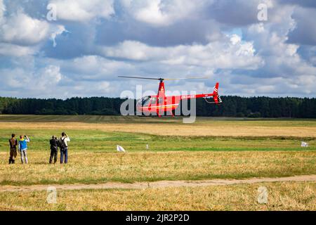 Private pleasure red helicopter on the takeoff site in the field. Lida, Belarus - August 29, 2017. Stock Photo