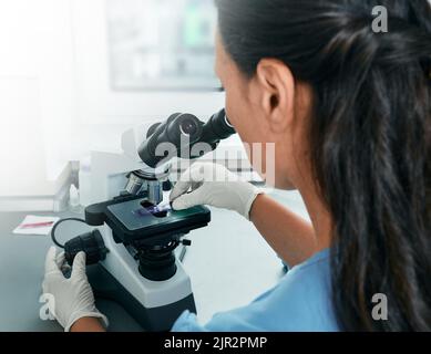 Laboratory assistant researching of test sample under medical microscope in science laboratory Stock Photo