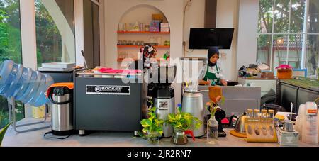 A view of the cozy cafe interior and baristas making coffee in Indonesia Stock Photo