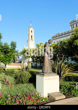 Bronze statue of San Diego de Alcala on the campus of the University of San Diego, in San Diego, California; Immaculata Parish tower in background. Stock Photo