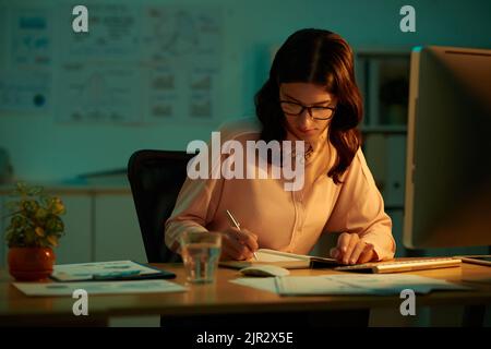 Female entrepreneur writing plans in her reminder Stock Photo