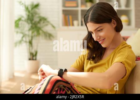 Beautiful smiling young woman checking time on her smart watch Stock Photo