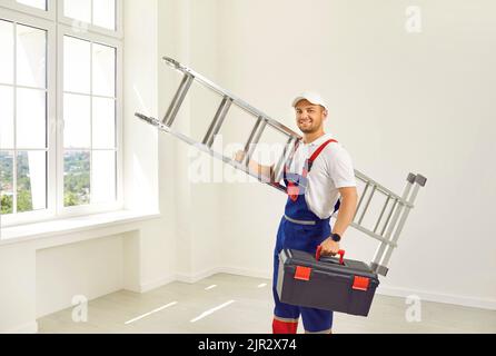 Portrait of professional male repairman with metal ladder and toolbox in his hands. Stock Photo