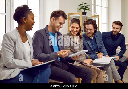 Young happy multiracial people men and woman working in modern company laugh sits in row in office Stock Photo