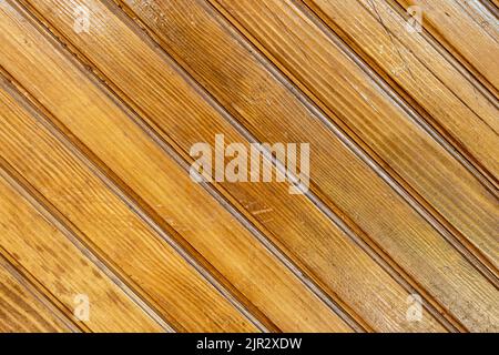Brown background texture of a wooden fence made of diagonal planks of natural wood. Wooden background from wooden planks. Stock Photo