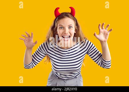 Studio portrait of happy funny young girl wearing devil horns as her Halloween costume Stock Photo