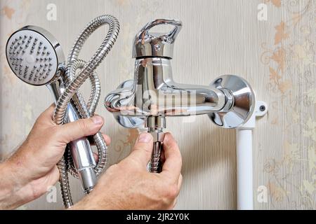 Plumber tightening fixing nut on flexible hose of shower head. Stock Photo