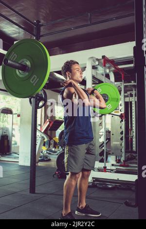 Fit young man lifting heavy barbell in gym Stock Photo