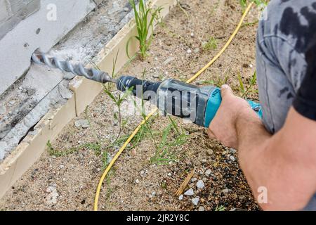 Electric hammer drill at building site is used to drill hole in wall. Stock Photo