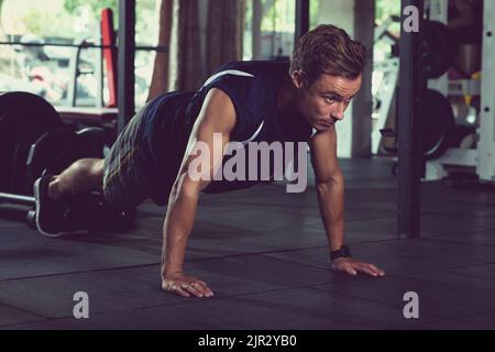 Fit young man doing push-ups in gym Stock Photo