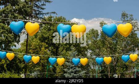 Garland in the form of yellow and blue hearts against the blue sky. The concept of support for Ukraine. Stock Photo