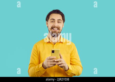 Happily satisfied handsome man uses mobile phone for online shopping, chatting or using service apps Stock Photo
