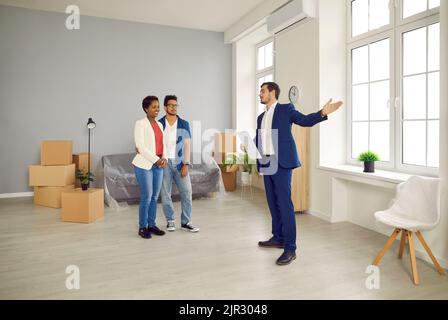 Realtor giving tour around the house to young couple who are planning to buy new home Stock Photo