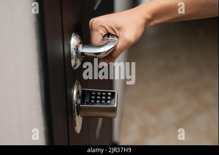 Woman opens the combination lock on the door to the apartment. Keyless entry.  Stock Photo