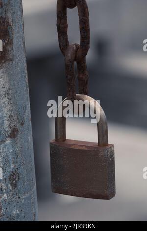 Locked padlock hanging from a rusty chain Stock Photo