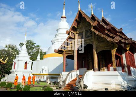 Chiang Mai, Thailand - November 14, 2013: Buddhist monks walking through the exterior of Wat Phra Singh located in Chiang Mai, Thailand. Stock Photo