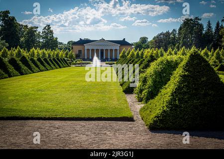 Uppsala Castle Park in Sweden with the Orangery in the background. The trellis of pyamid cut fir trees has a blemish Stock Photo