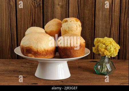 Kulich, Russian easter yeast sweet breads on white pedestal with yellow flowers on wooden background horizontal Stock Photo