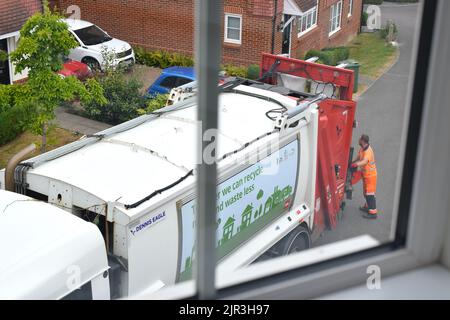 Rubbish truck and a worker on residential street. Stock Photo
