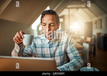 Enjoying some free wifi over coffee. a young entrepreneur using his laptop in a coffee shop. Stock Photo