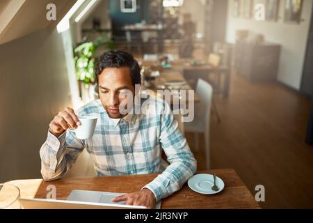And they wonder why his work is never behind. a young entrepreneur using his laptop in a coffee shop. Stock Photo