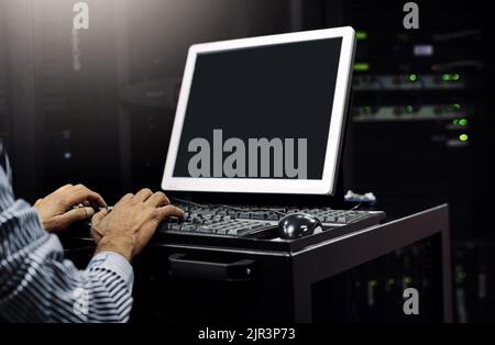 Your computer network, in expert hands. an unrecognizable IT technician using a computer while working in a server room. Stock Photo