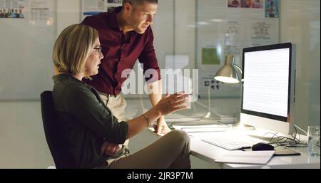 Working it out together. two businesspeople working together on a computer in their office. Stock Photo