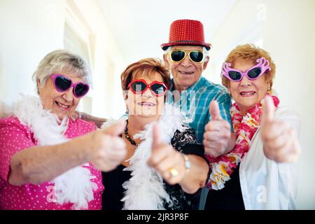 Heres to us the cool kids. a group carefree elderly people wearing sunglasses and showing thumbs up to the camera. Stock Photo