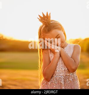 She likes to pretend to sleep while standing. an adorable little girl playing outdoors. Stock Photo