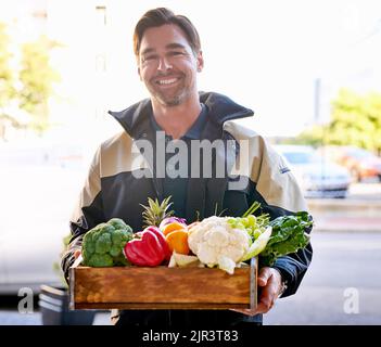 Delivered fresh straight to you. Portrait of a courier making a grocery delivery. Stock Photo